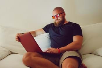man wearing blue light blocking eye glasses working with laptop