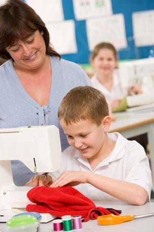 teacher showing a boy how to use a sewing machine