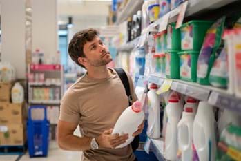 man shopping and trying to choose the most eco friendly detergent