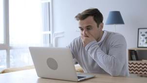 man looking shocked at laptop after thinking he has been tricked